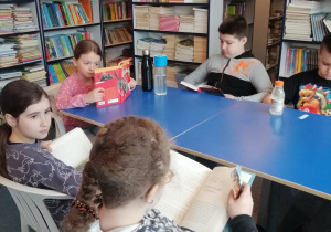 Uczniowie na przerwie czytają książki w bibliotece szkolnej.