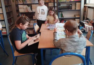 uczniowie klas młodszych siedzą przy nowych stolikach i czytają książki