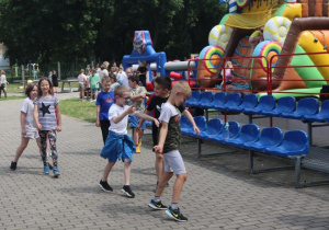 Uczniowie i nauczyciele podczas zabaw i gier rekreacyjnych na boisku szkolnym zorganizowanych z okazji Dnia Dziecka