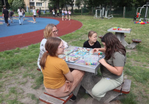 Uczniowie i nauczyciele podczas zabaw i gier rekreacyjnych na boisku szkolnym zorganizowanych z okazji Dnia Dziecka