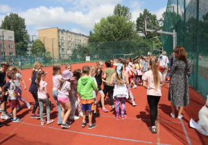 Uczniowie i nauczyciele podczas zabaw i gier rekreacyjnych na boisku szkolnym zorganizowanych z okazji Dnia Dziecka