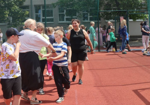 Uczniowie i nauczyciele podczas zabaw i gier rekreacyjnych na boisku szkolnym zorganizowanych z okazji Dnia Dziecka