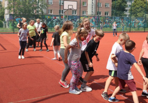 Uczniowie i nauczyciele podczas zabaw i gier rekreacyjnych na boisku szkolnym zorganizowanych z okazji Dnia Dziecka