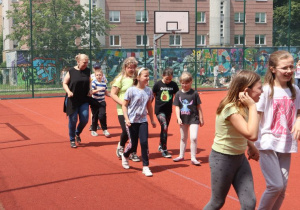 Uczniowie i nauczyciele podczas zabaw i gier rekreacyjnych na boisku szkolnym zorganizowanych z okazji Dnia Dziecka