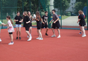 Uczniowie i nauczyciele podczas zabaw i gier rekreacyjnych na boisku szkolnym zorganizowanych z okazji Dnia Dziecka